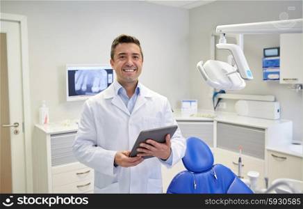 people, medicine, stomatology and healthcare concept - happy middle aged male dentist in white coat with tablet pc computer at dental clinic office