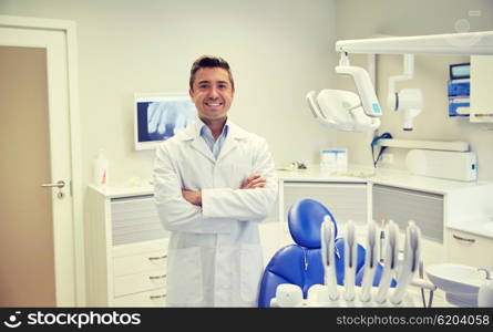 people, medicine, stomatology and healthcare concept - happy middle aged male dentist in white coat at dental clinic office