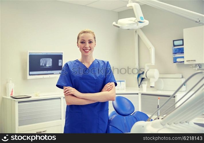 people, medicine, stomatology and healthcare concept - happy young female dentist at dental clinic office