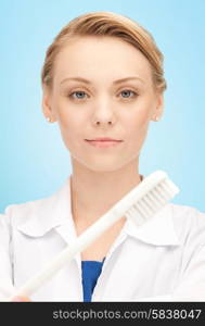 people, medicine, stomatology and healthcare concept - happy young female dentist with tooth brush over blue background