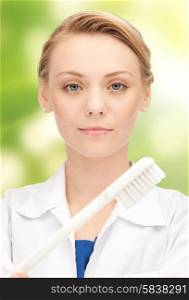 people, medicine, stomatology and healthcare concept - happy young female dentist with tooth brush over green background