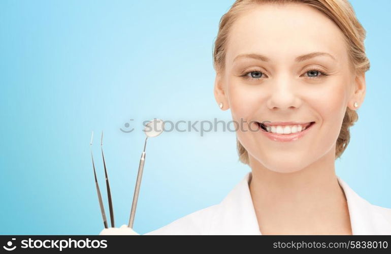 people, medicine, stomatology and healthcare concept - happy young female dentist with tools over blue background