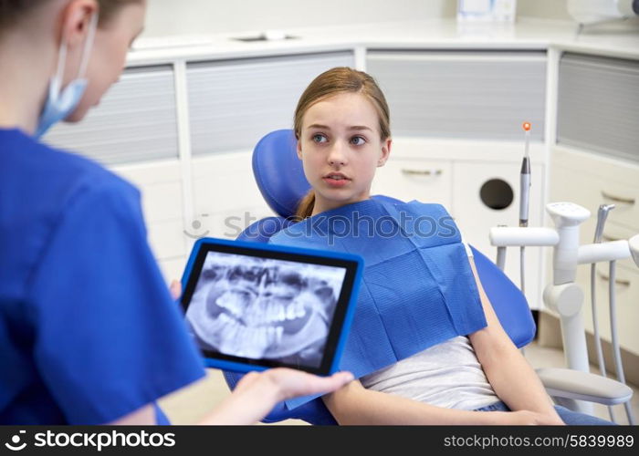 people, medicine, stomatology, technology and health care concept - female dentist showing teeth x-ray on tablet pc computer to patient girl at dental clinic office