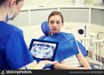people, medicine, stomatology, technology and health care concept - female dentist showing teeth x-ray on tablet pc computer to patient girl at dental clinic office