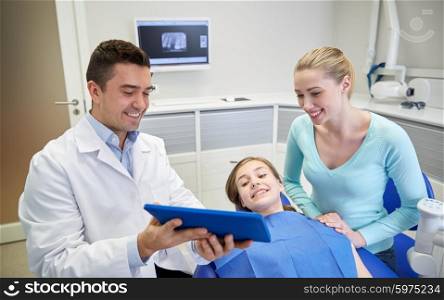 people, medicine, stomatology, technology and health care concept - happy male dentist showing tablet pc computer to patient girl and her mother at dental clinic office
