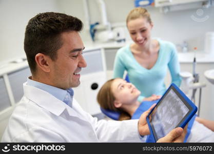 people, medicine, stomatology, technology and health care concept - happy male dentist looking at teeth x-ray on tablet pc computer and patient girl with her mother at dental clinic office