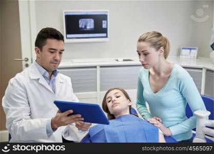 people, medicine, stomatology, technology and health care concept - male dentist showing tablet pc computer to patient girl and her mother at dental clinic office