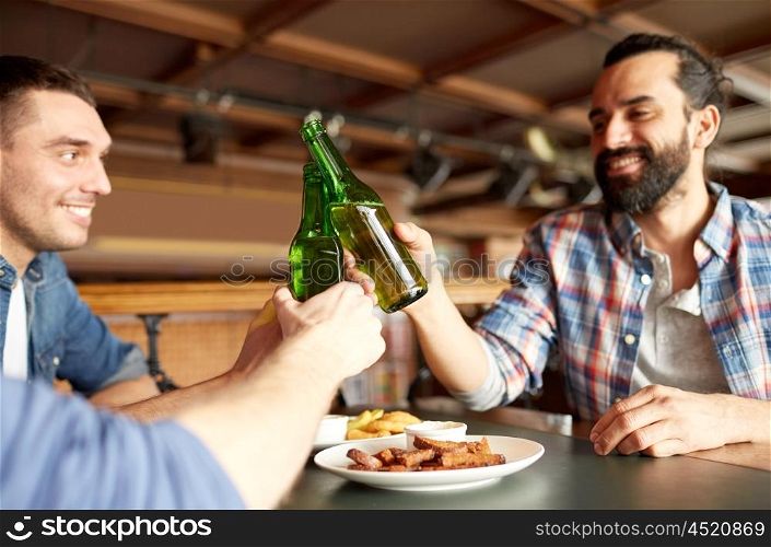 people, men, leisure, friendship and celebration concept - happy male friends drinking beer and clinking bottles at bar or pub