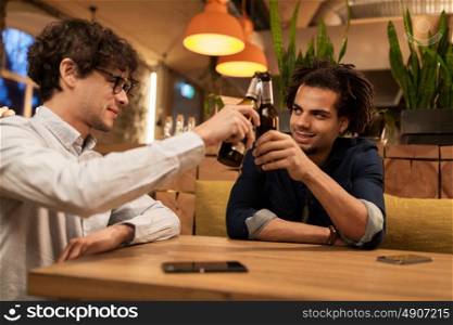 people, men, leisure, friendship and celebration concept - happy male friends drinking beer and clinking bottles at bar or pub. happy male friends drinking beer at bar or pub