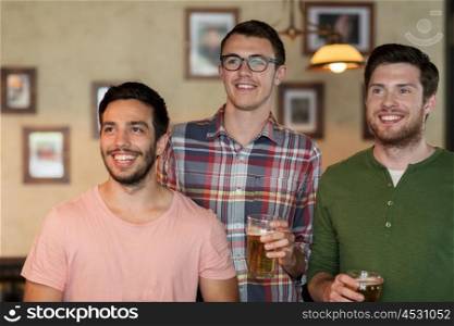 people, men, leisure, friendship and celebration concept - happy male friends with beer glasses watching sport game or football match at bar or pub