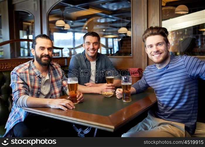 people, men, leisure, friendship and communication concept - happy male friends drinking draft beer at bar or pub