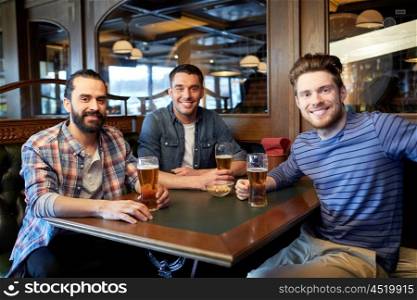 people, men, leisure, friendship and communication concept - happy male friends drinking draft beer at bar or pub