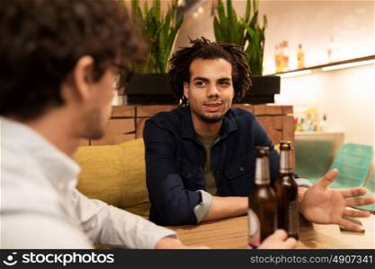 people, men, leisure, friendship and communication concept - happy male friends drinking bottled beer and talking at bar or pub. happy male friends drinking beer at bar or pub
