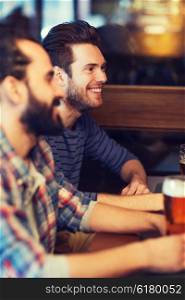 people, men, leisure, friendship and communication concept - happy male friends drinking beer at bar or pub