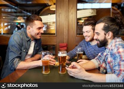 people, men, leisure, friendship and communication concept - happy male friends with smartphones drinking draft beer at bar or pub