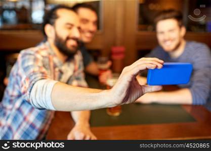 people, men, leisure, friendship and technology concept - happy male friends drinking beer and taking selfie by smartphone at bar or pub