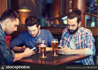 people, men, leisure, friendship and technology concept - male friends with smartphones drinking beer at bar or pub