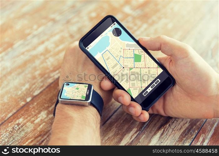 people, modern technology, application and navigation concept - close up of male hand holding smart phone and wearing watch with gps and road map on screen
