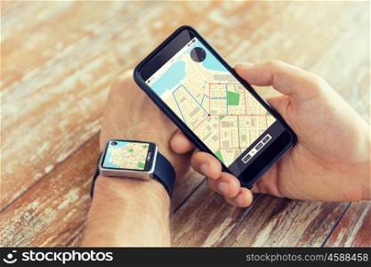 people, modern technology, application and navigation concept - close up of male hand holding smart phone and wearing watch with gps and road map on screen
