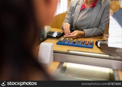people, money, saving and finance concept - clerk counting coins for customer at bank office or currency exchanger