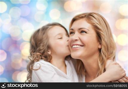people, motherhood, family and adoption concept - happy mother and daughter hugging and kissing over blue holidays lights background