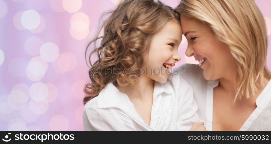 people, motherhood, family, holidays and adoption concept - happy mother and daughter hugging over holidays lights background