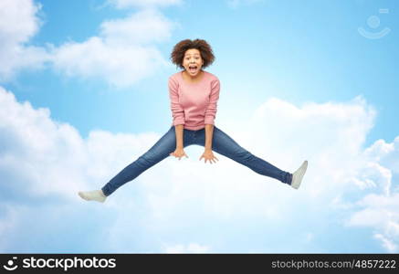 people, motion and action concept - happy african american young woman jumping over blue sky and clouds background