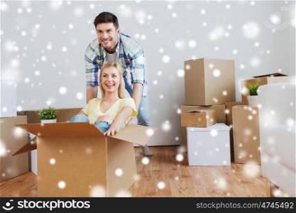 people, moving and real estate concept - happy couple having fun and riding in cardboard boxes at new home over snow