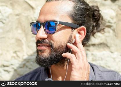 people, music, technology, leisure and lifestyle - hipster man with earphones and listening to music outdoors
