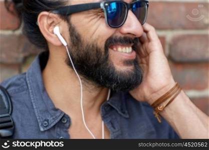 people, music, technology, leisure and lifestyle - hipster man with earphones and listening to music outdoors
