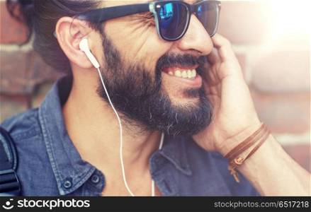 people, music, technology, leisure and lifestyle - hipster man with earphones and listening to music outdoors. man with earphones listening to music outdoors. man with earphones listening to music outdoors