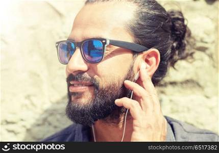 people, music, technology, leisure and lifestyle - hipster man with earphones and listening to music outdoors. man with earphones listening to music outdoors. man with earphones listening to music outdoors