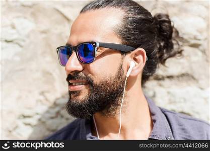 people, music, technology, leisure and lifestyle - hipster man with earphones on city street listening to music