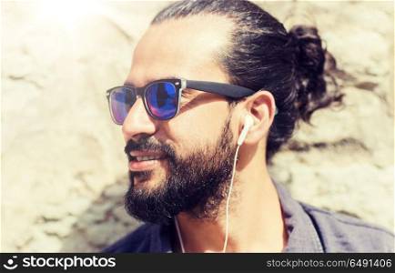 people, music, technology, leisure and lifestyle - hipster man with earphones on city street listening to music. happy man with earphones listening to music. happy man with earphones listening to music