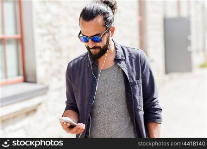 people, music, technology, leisure and lifestyle - man with earphones and smartphone walking in city