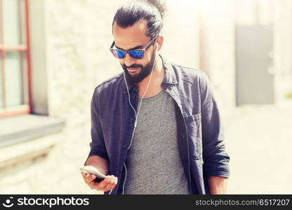 people, music, technology, leisure and lifestyle - man with earphones and smartphone walking in city. man with earphones and smartphone walking in city. man with earphones and smartphone walking in city