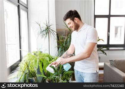 people, nature and plants care concept - man spraying houseplants by water sprayer at home. man spraying houseplants with water at home