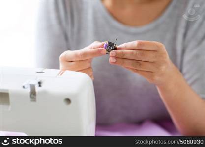 people, needlework and tailoring concept - tailor woman with thread and spool of sewing machine at studio. tailor woman with spool of sewing machine