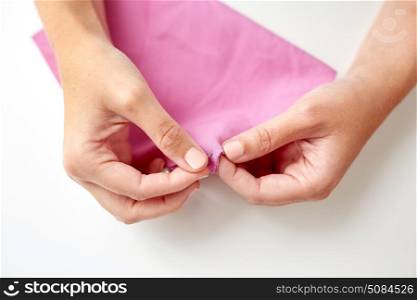 people, needlework, sewing and tailoring concept - tailor woman with thread in needle stitching fabric pieces together. woman with needle stitching fabric pieces. woman with needle stitching fabric pieces