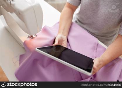 people, needlework, technology and tailoring concept - tailor woman with sewing machine, tablet pc and fabric. tailor with sewing machine, tablet pc and fabric. tailor with sewing machine, tablet pc and fabric