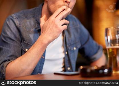 people, nicotine addiction and bad habits concept - close up of man drinking beer and smoking cigarette at bar or pub