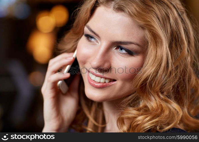 people, nightlife, technology and holidays concept - young woman calling on smartphone at night club or bar