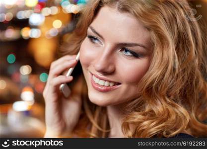 people, nightlife, technology and holidays concept - young woman calling on smartphone at night club or bar