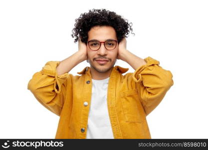 people, noise and stress concept - man in yellow jacket closing ears by hands over white background. man in yellow jacket closing ears by hands