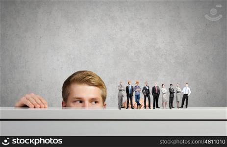People of different professions. Businessman looking from under the table at businessteam