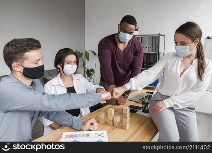 people office during pandemic having meeting fist bumping each other