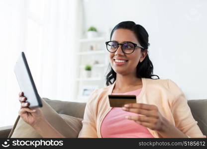 people, online shopping and finances concept - happy indian woman with tablet pc and credit card at home. happy woman with tablet pc and credit card at home