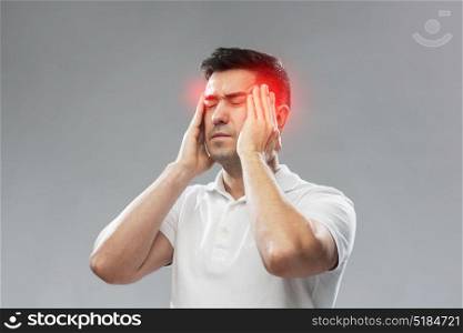 people, pain and stress concept - unhappy man suffering from head ache and touching his temples over gray background. unhappy man suffering from head ache