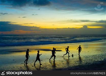 People palying soccer on the beach at sunset. Bali island, Indonesia