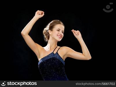 people, party, holidays and glamour concept - smiling woman dancing with raised hands over black background